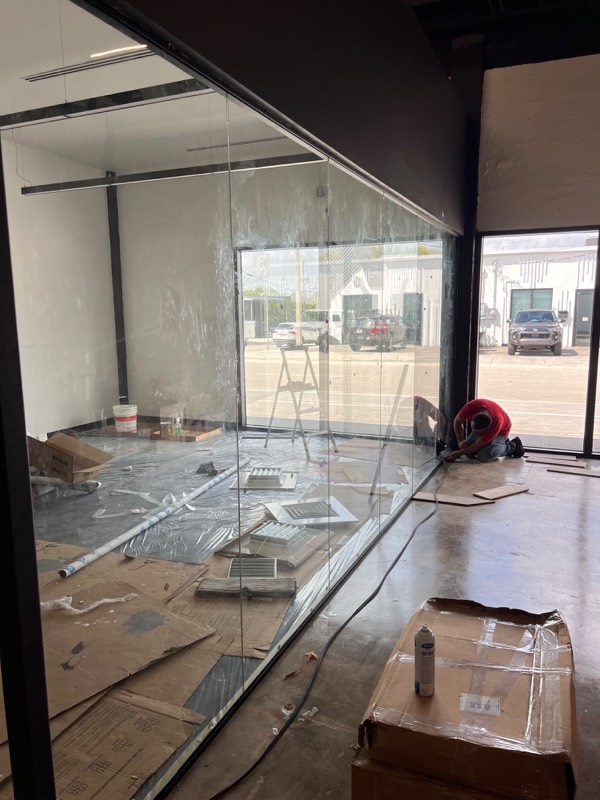 Installer finishing the base of a full-height glass wall