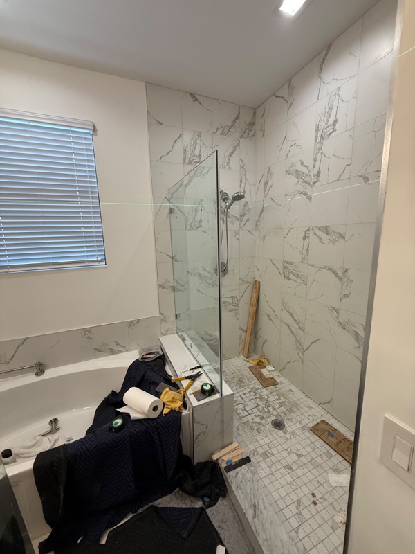 Fixed shower glass panel standing on the bench before the door is hung