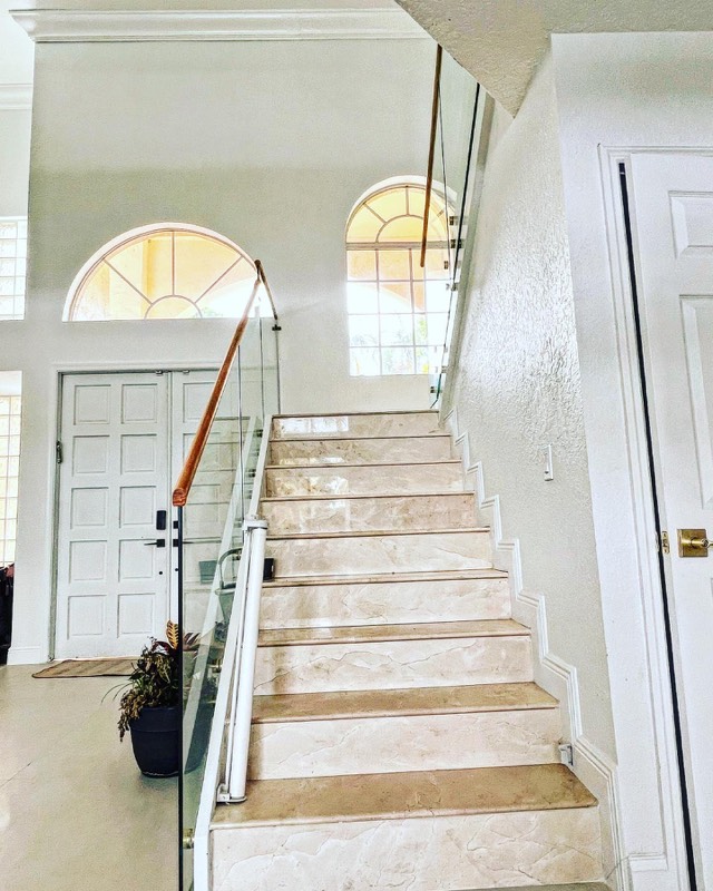 Marble staircase with glass railing and wood handrail