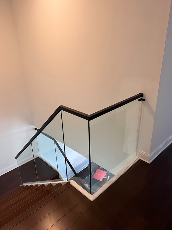 Glass railing with a black handrail at the top of a staircase