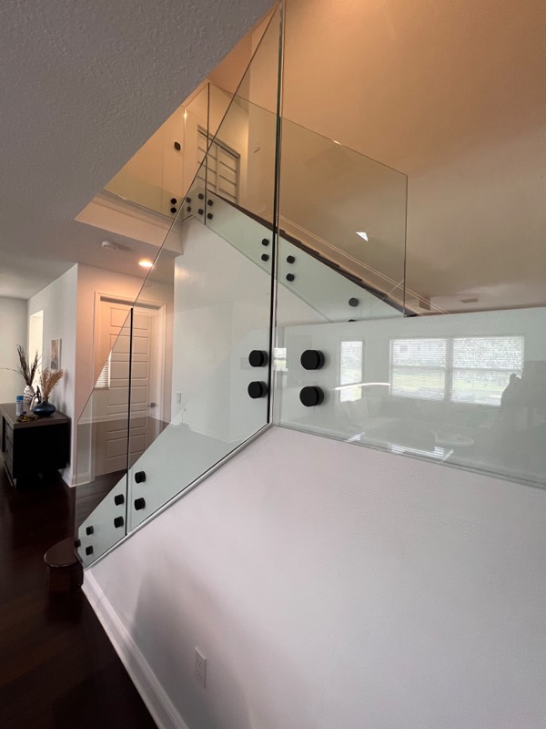 Close view of glass railing panels and round black standoffs