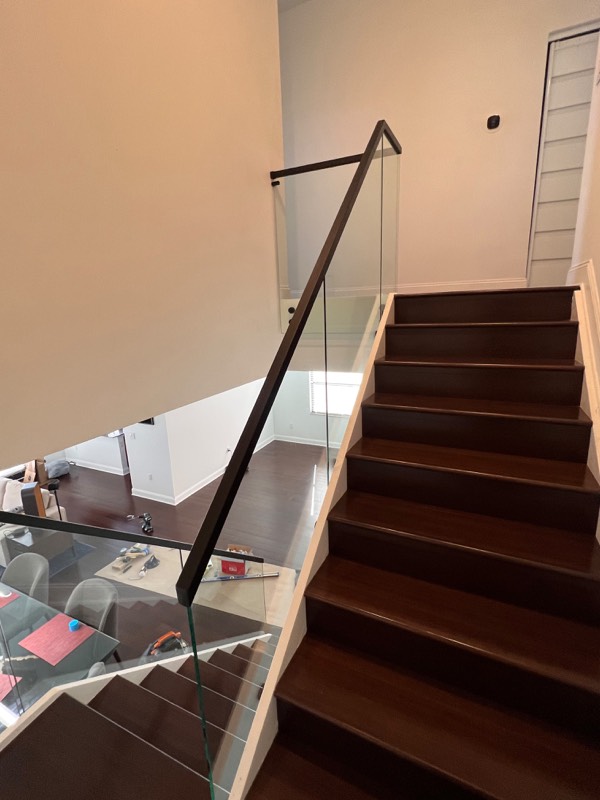 Glass railing and black handrail seen from the stairs