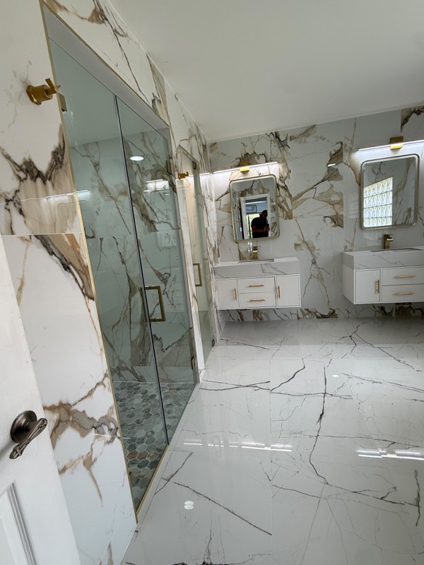Side view of a gold trimmed glass shower enclosure in a marble bathroom
