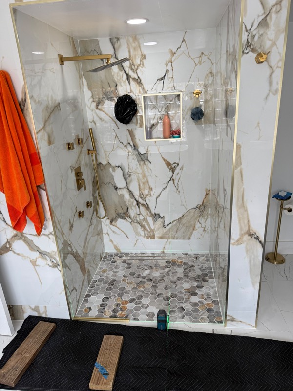 Marble shower opening with gold channel fitted before the glass goes in