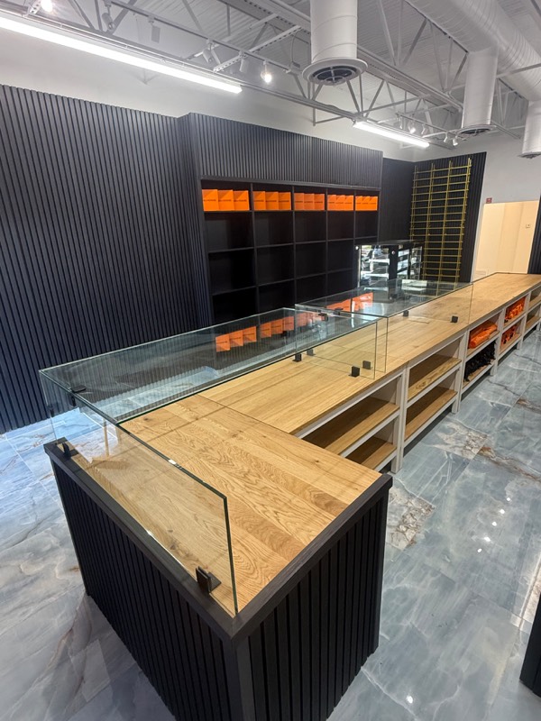 Glass counter guard with black fittings on a long wood shop counter