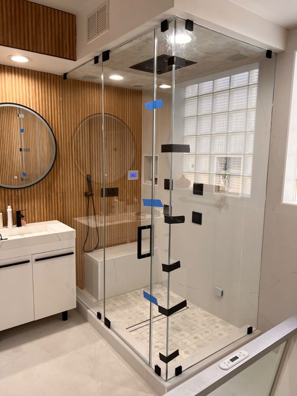 Floor to ceiling frameless steam shower enclosure with matte black hardware