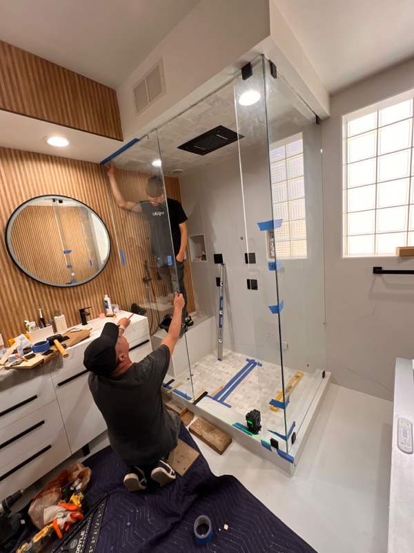 Two installers setting a tall shower glass panel