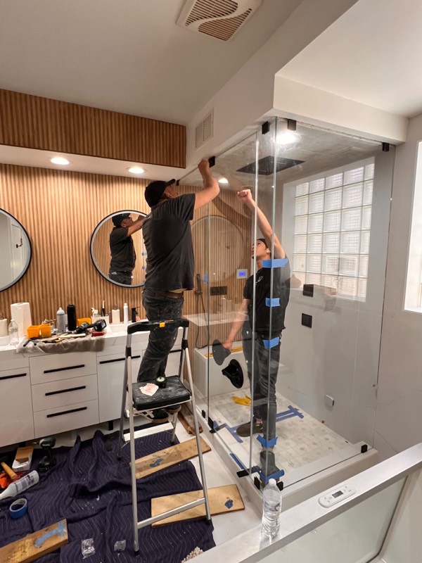 Installers fixing the top of a floor to ceiling shower panel