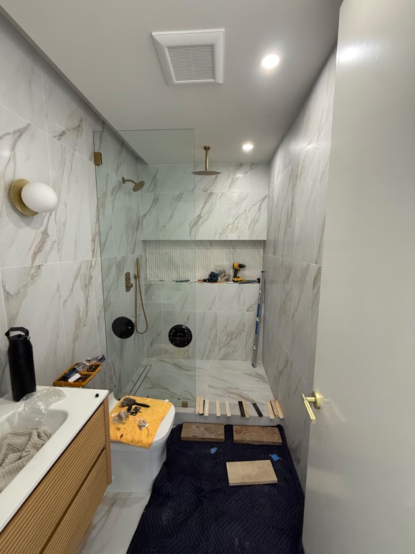 Walk-in shower with a frameless fixed glass panel and gold fixtures
